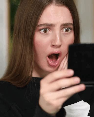 a woman is holding up her cell phone to take a selfie with it's mouth wide open