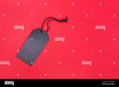 Blank black tag on red background with copy space. Price tag, gift tag, sale tag, address label ...
