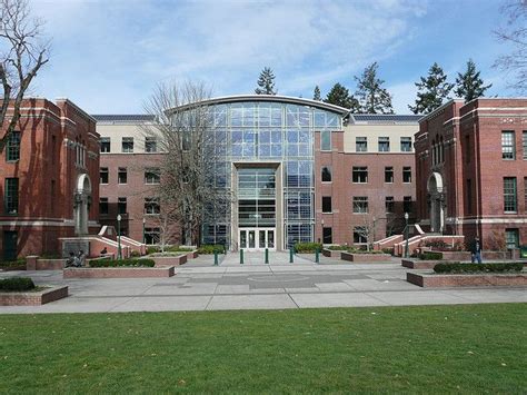 the building has many windows on it and is surrounded by green grass ...