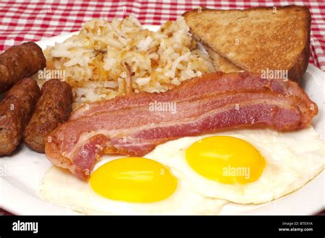 Breakfast plate with eggs sunny side up, bacon, link sausage, hash ...