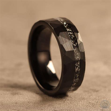 a black ring with an intricate design on the outside and inside, sitting on a surface