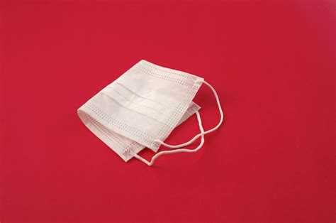 Premium Photo | White mask on the side on a red surface protective mask used in medicine ...