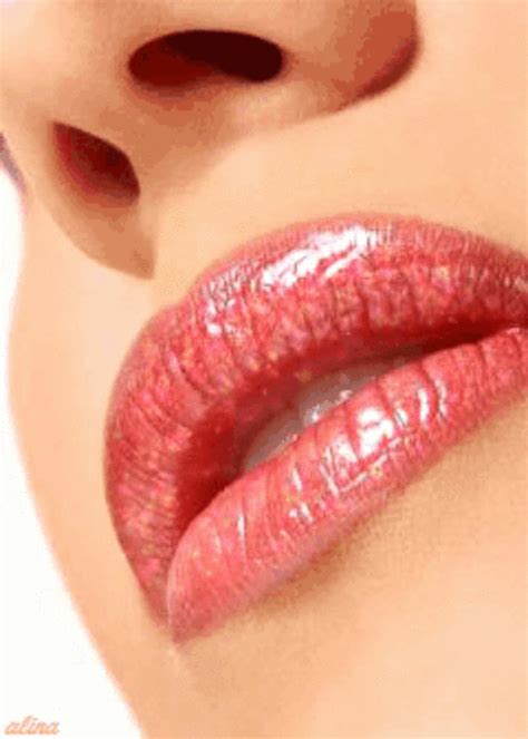 a woman's lips with shiny red lipstick on her cheek and the bottom part of her face