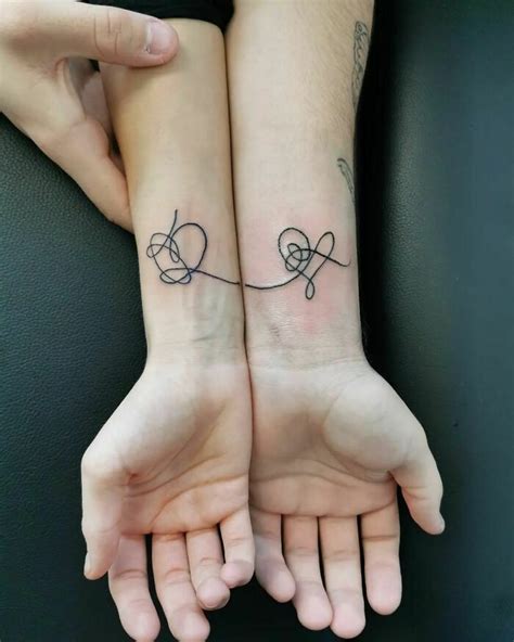 two people with matching tattoos on their arms, one holding the other's ...