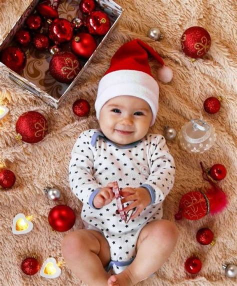 a baby wearing a santa hat sitting next to christmas ornaments