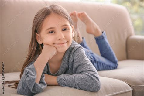Cute little girl lying on sofa at home Stock Photo | Adobe Stock