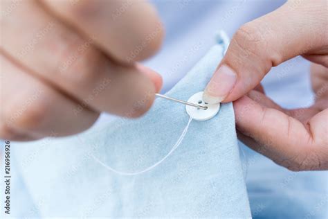 Hands of a woman sew a button with a needle close up. Woman is sewing buttons a shirt. Stock ...