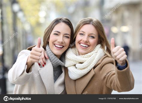 Two friends smiling at camera with thumbs up in winter Stock Photo by ...