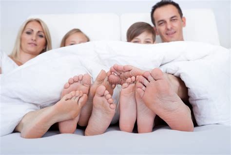 Família Feliz Na Cama Sob a Tampa Que Mostra Os Pés Foto de Stock ...