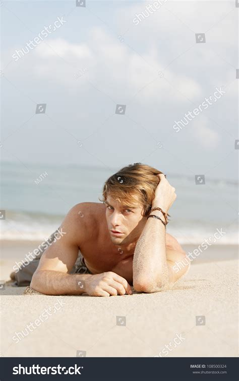 Young Attractive Man Laying Down On A Beach, With The Sea In The ...