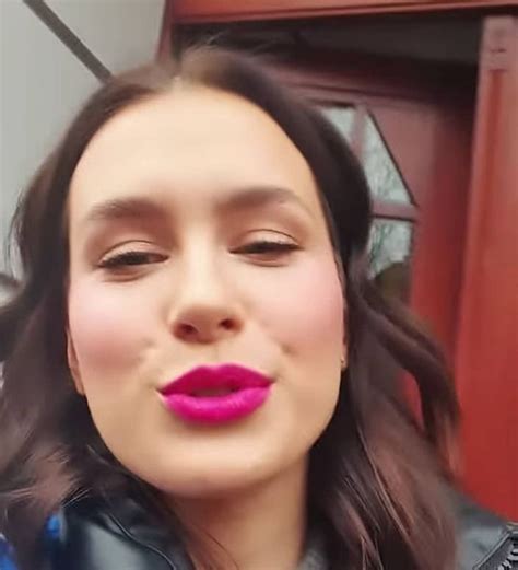 a woman with long dark hair and pink lipstick is taking a selfie in front of a red door