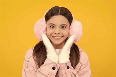 Premium Photo | Happy kid in winter mittens and earmuffs on yellow background winter