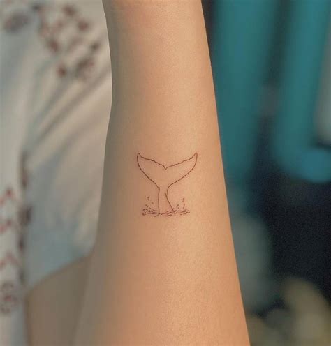 Fine line whale tail tattoo on the forearm