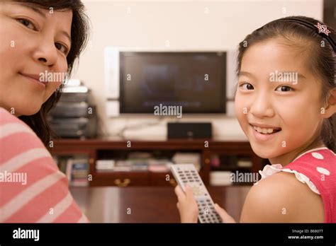 Portrait of a girl holding a remote control and smiling with her mother Stock Photo - Alamy