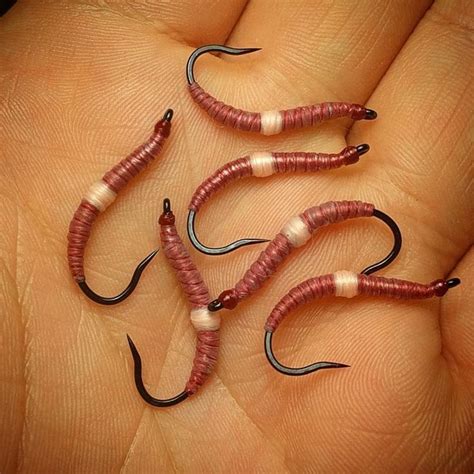 three red and white worms in the palm of someone's hand