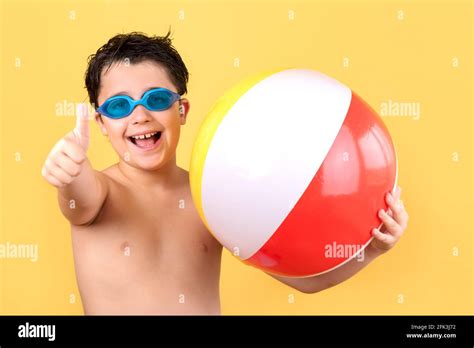 happy child with swim goggles playing with Beach ball on yellow background.Summer Vacation fun ...