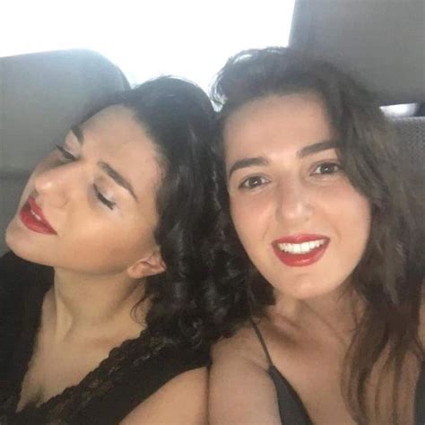 two women sitting in the back seat of a car, one with red lipstick on her lips