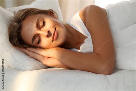 Beautiful young woman sleeping while lying in bed comfortably and ...