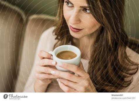 Portrait of woman sitting on couch drinking cup of white coffee - a Royalty Free Stock Photo ...