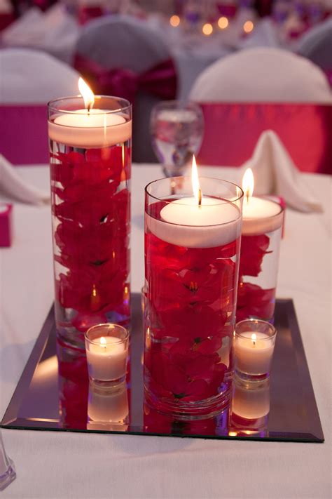 candles are lit on the table with roses in vases