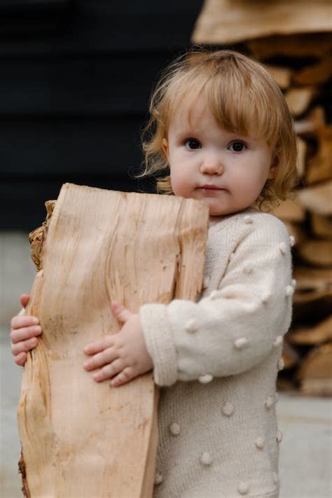 Little girl standing in garden near firewood · Free Stock Photo