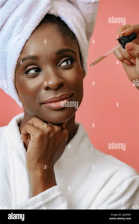 Portrait of a young woman thinking in bathrobe with spa towel on head receiving treatment with ...