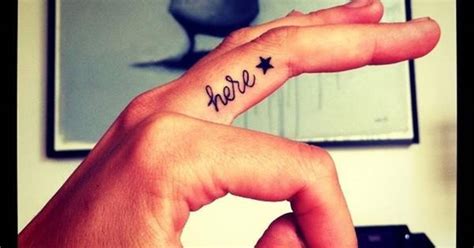 Middle finger tattoo saying "here" followed by a black