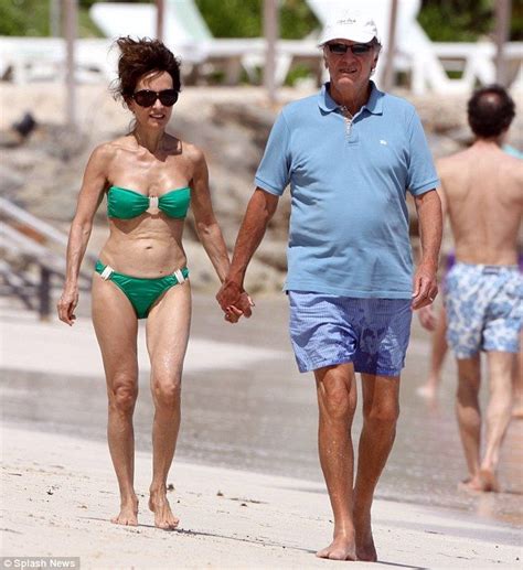 an older man and woman walking on the beach