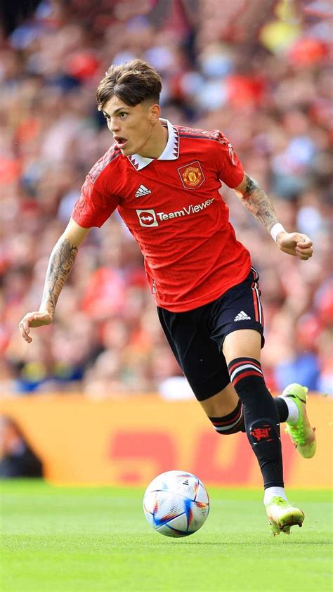 a man in red shirt kicking a soccer ball on field with crowd watching ...