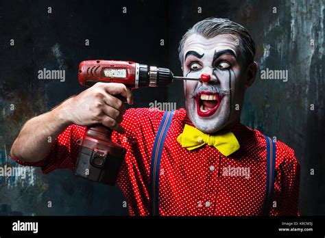 The scary clown and electric drill on dack background. Halloween Stock Photo: 169309662 - Alamy