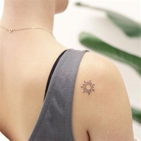 Minimalist sun tattoo on the shoulder.