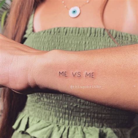 "Me vs Me" lettering tattoo on the wrist.