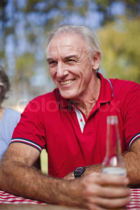 Older man drinking at picnic table | Stock image | Colourbox
