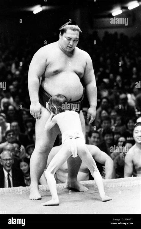 A seven-year-old Japanese boy attempts to throw champion Sumo wrestler Kitanoumi, 20, to the ...