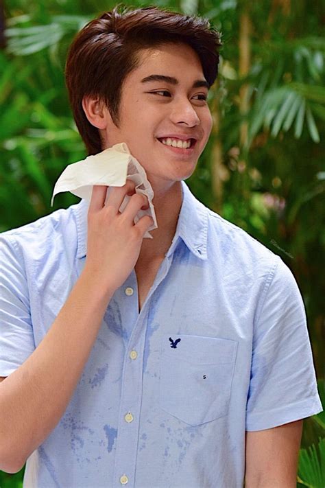 a young man is smiling as he wipes his face with a tissue paper towel