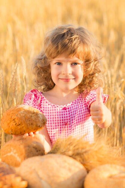 Premium Photo | Happy child holding bread against yellow autumn wheat field