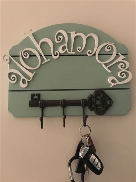 there is a key holder on the wall with a name and keys hanging from it