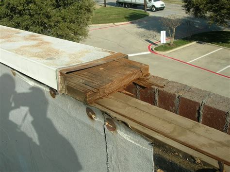 Metal coping, or cap flashing, being removed from a parapet wall