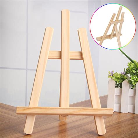 wooden easel standing on top of a table next to vases and potted plants