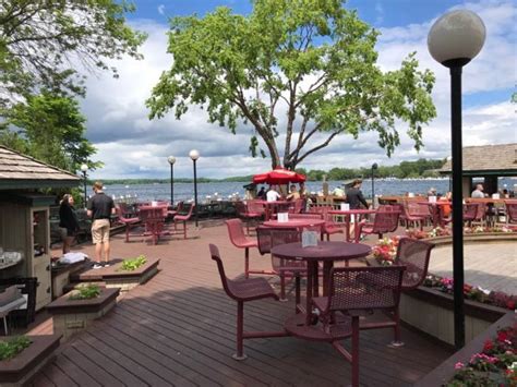 an outdoor patio with tables and chairs near the water