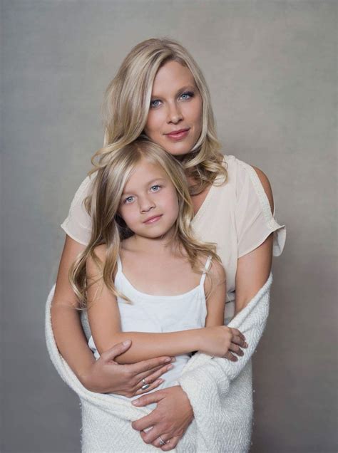 a mother and daughter hugging each other in front of a gray background