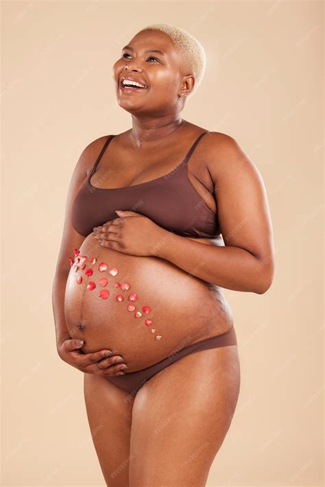 Pregnant black woman and smile with flowers on belly in studio for body