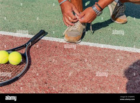 close  shot shows  man tying  shoe   tennis court