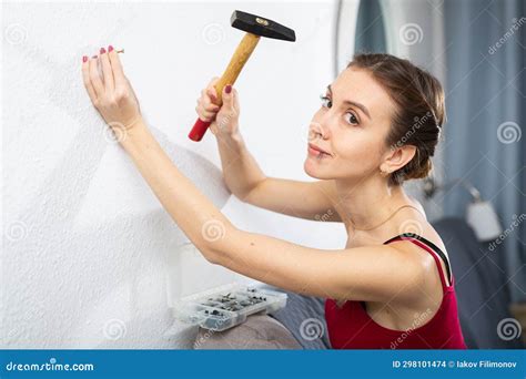 young woman hammering  nail   wall  hammer stock photo