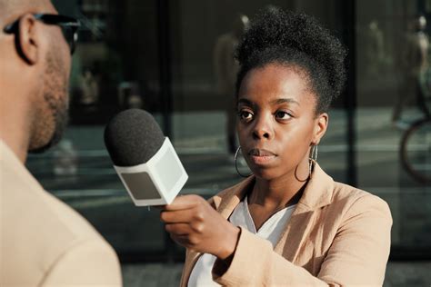 African female journalist holding microphone and interviewing the man ...