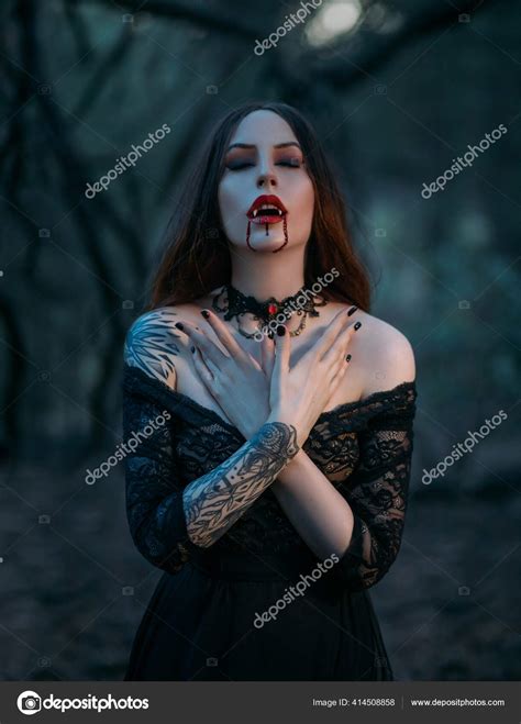 Attractive sexy vampire woman with sharp teeth fangs drops of blood