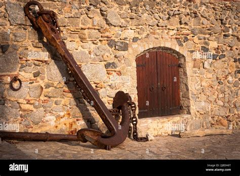 A big anchor and a tiny door for boats on the Spanish Coast Brava. Rock ...