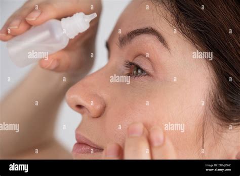 Caucasian woman dripping moisturizing drops into her eyes Stock Photo ...