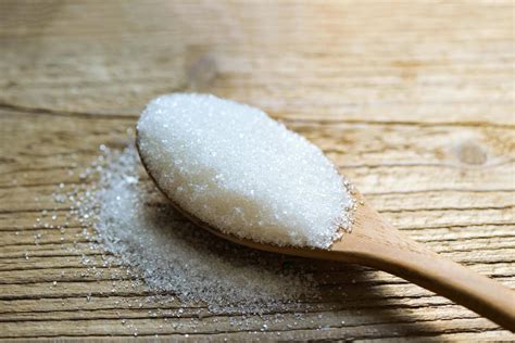 Sugar on spoon and wooden background, white sugar for food and sweets