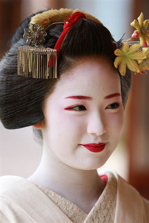 a geisha woman in traditional japanese dress and hair comb with flowers